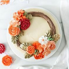 a cake decorated with flowers on top of a white platter next to other decorations