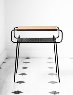 a wooden table sitting on top of a black metal frame in the middle of a tiled floor