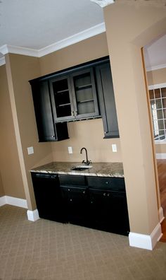 an empty kitchen with black cabinets and granite counter tops in a house that is being remodeled