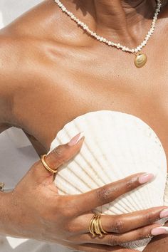 a woman in a white dress holding a shell with her right hand on top of it