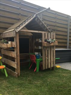 a child's play house made out of pallets and wooden planks in the grass