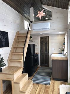 a kitchen and stairs in a tiny home with wood flooring, white walls and ceiling