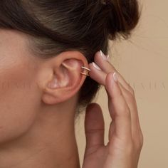 a woman is wearing an ear piercing in the shape of a cross on her left ear