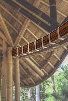 the inside of a bamboo structure with wooden beams and wood slats hanging from it's ceiling