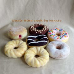 a bunch of doughnuts sitting on top of a white tablecloth with the words needle felt crafts by winnie