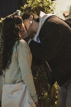 a man and woman kissing each other outside