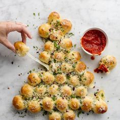 a christmas tree made out of rolls with sauce and parmesan cheese on top