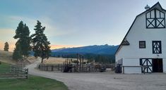 a white barn sitting on the side of a dirt road