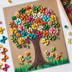 an art project made out of paper with colorful flowers and leaves on the tree's trunk