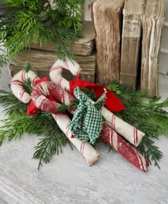 some wrapped candy canes sitting on top of a table next to christmas greenery