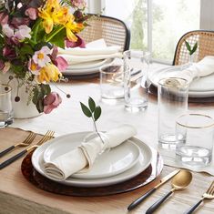 the table is set with plates, silverware and flowers