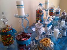 an assortment of candy and candies displayed on a blue table cloth with candles in the background