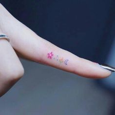 a person's finger with stars and moon tattoos on it