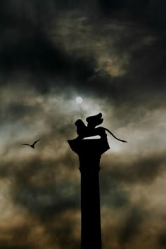 the silhouette of two people on top of a clock tower with clouds in the background