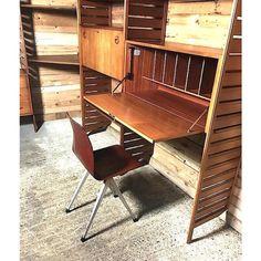 a wooden desk with a chair underneath it in a room filled with wood paneled walls