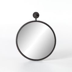 a round mirror on a white background with a black metal frame and an iron hook