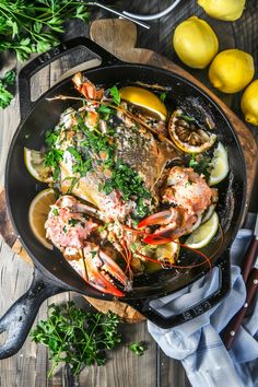 lobsters, lemons and parsley in a skillet on a wooden table