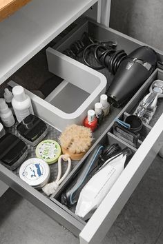 an organized drawer in a bathroom with hairdryers and other personal care items on it