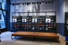 the inside of a shoe store with many pairs of shoes hanging on the wall and wooden bench