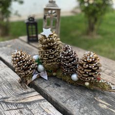 three pine cones sitting on top of a wooden table next to a lantern and some ornaments