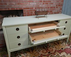 a green dresser with drawers and a fire place in the background