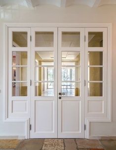 two white double doors with glass panels on each side in a room that has stone flooring