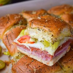 a sandwich cut in half sitting on top of a white plate next to pickles