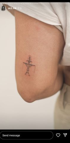 a small cross tattoo on the back of a woman's thigh