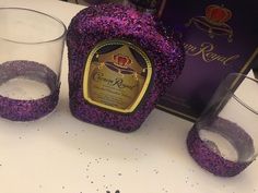 two glasses and a bottle of wine on a table next to a purple sign that says crown royal