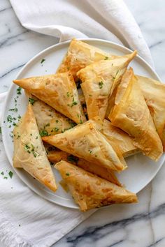 a white plate topped with cheesy pastries on top of a marble counter