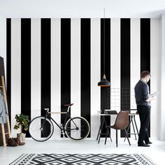 a man standing in front of a black and white striped wall next to a bike