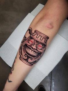 a tattoo on the arm of a person with a clown mask and eyeballs in it