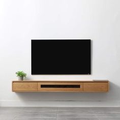 a flat screen tv sitting on top of a wooden shelf next to a potted plant