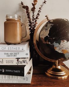 a stack of books sitting on top of a wooden table next to a vase filled with flowers