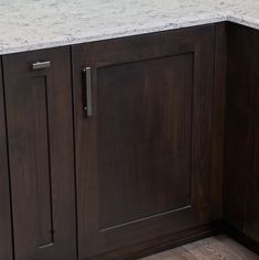 a kitchen counter with marble top and dark wood cabinetry on the bottom, in front of a window