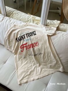 a t - shirt that says saint trope is on top of a white bed