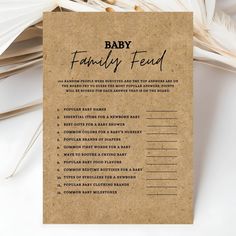 a baby's family feed card sitting on top of a pile of white feathers