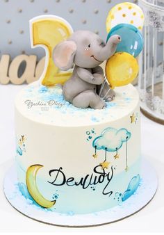 a baby elephant sitting on top of a blue and yellow cake