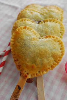 three heart shaped pastries on wooden sticks