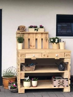 a wooden shelf with potted plants sitting on it's sides next to a building