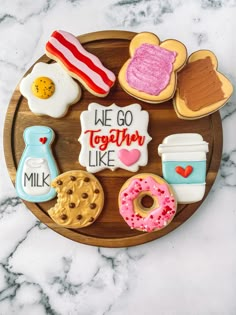 decorated cookies arranged on a wooden platter that says we go together like milk, donuts, and coffee