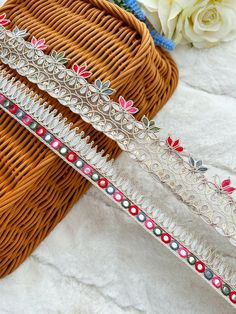 three different types of beaded bracelets on a white surface next to a basket with flowers