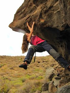 a woman climbing up the side of a large rock