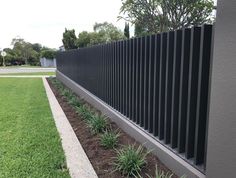 a black metal fence next to grass and trees