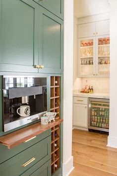 a kitchen with green cabinets and wooden flooring is pictured in this image, there is a coffee maker on the counter