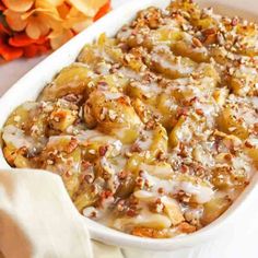 a casserole dish filled with bananas and pecans in a white baking dish