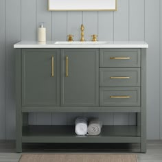 a bathroom vanity with two gold handles and white marble counter top, next to a gray wall