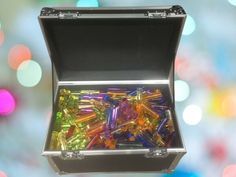 a box filled with lots of different colored glass beads on top of a table next to colorful lights