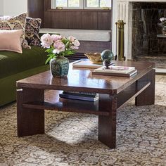 a living room with a green couch and coffee table in front of a fire place