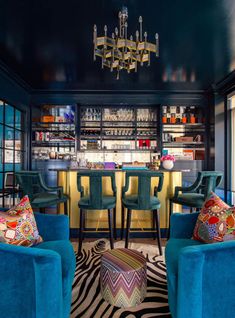 a room with blue chairs and a bar in the backround, surrounded by zebra rugs